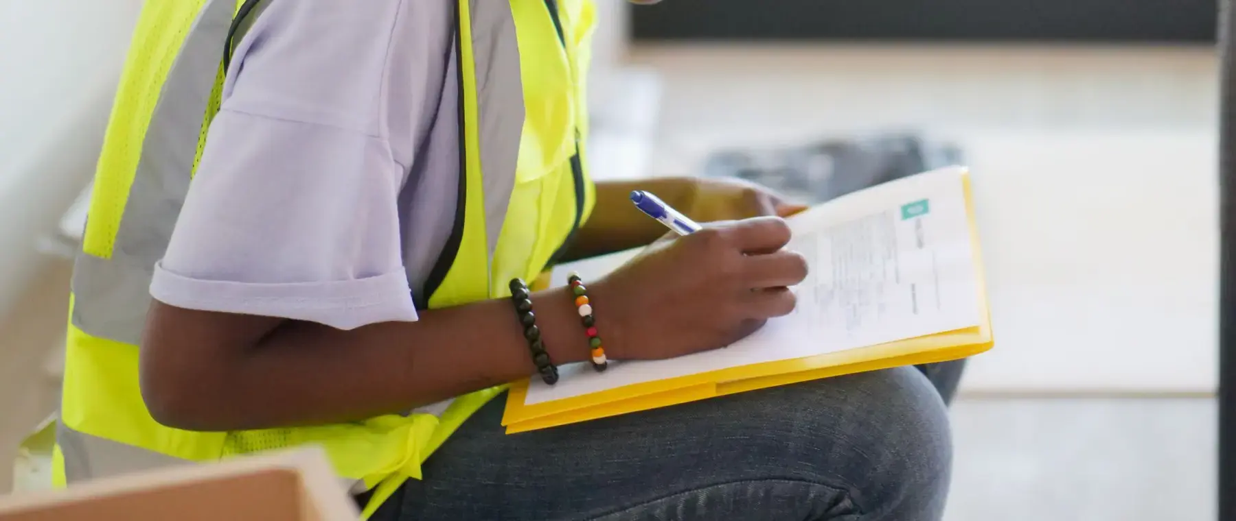 Site engineer in a hard hat and high visibility vest completing a checklist on a clipboard