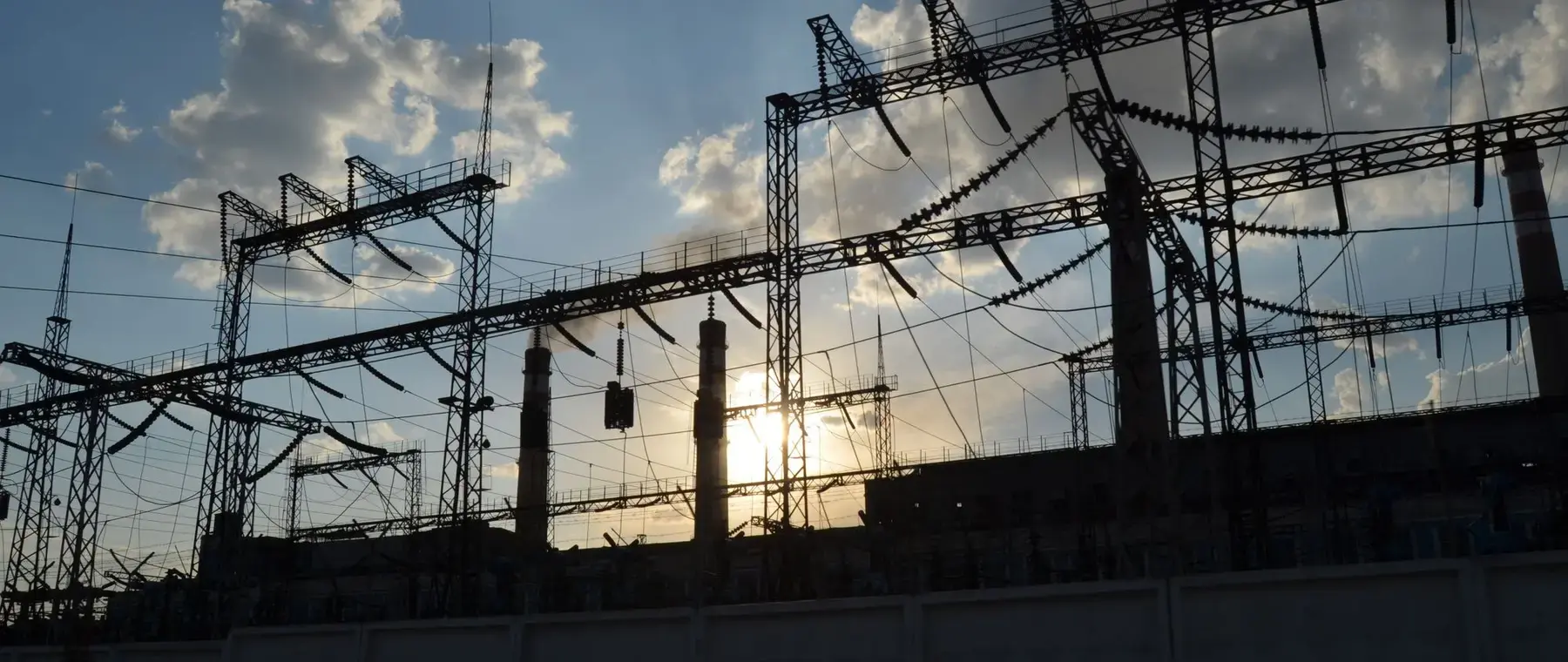 High voltage switchyard silhouetted against a dusk sky