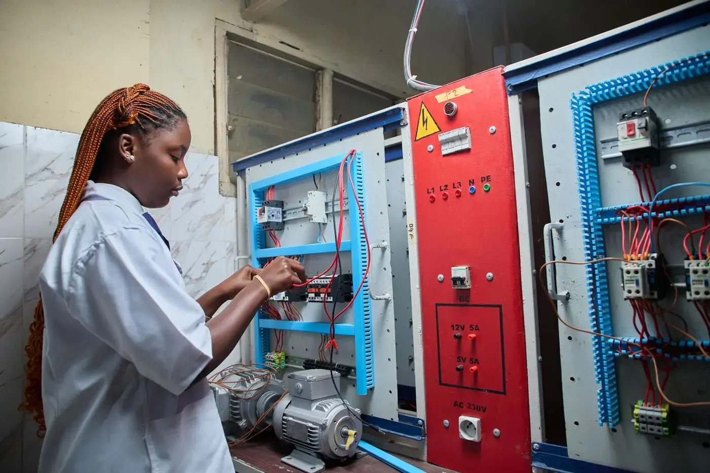 Technician working inside an open electrical control panel, checking wiring against the schematic