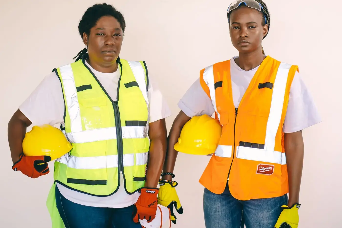 Two site workers in high visibility vests holding hard hats before starting work