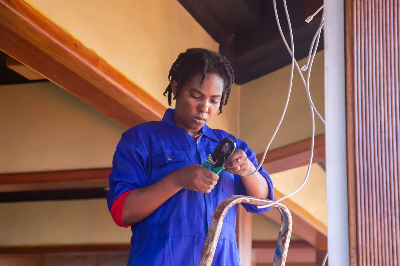Electrician in overalls terminating cables during building maintenance work